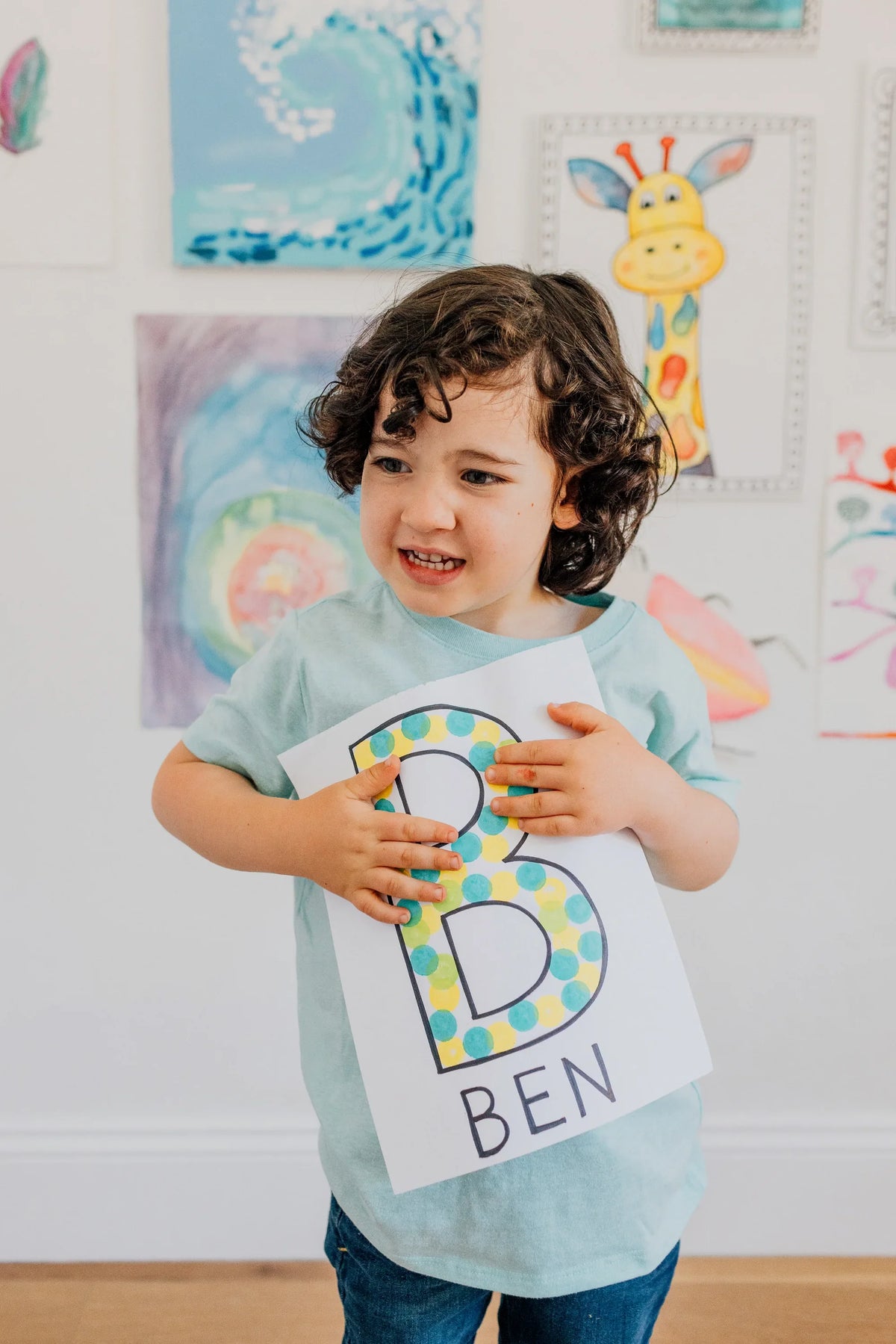 Boy holding up the letter B he filled in with dots