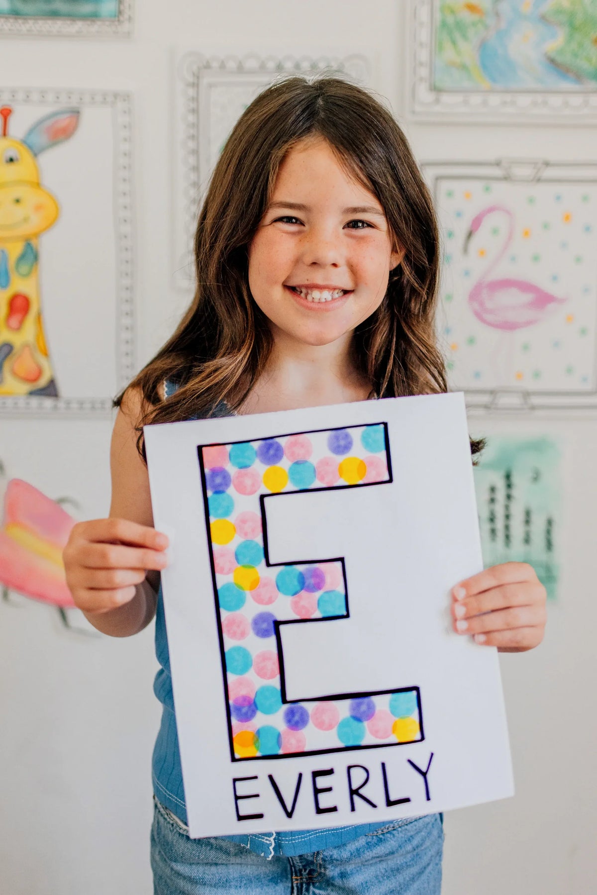 Girl holding up the letter E she filled in with dots
