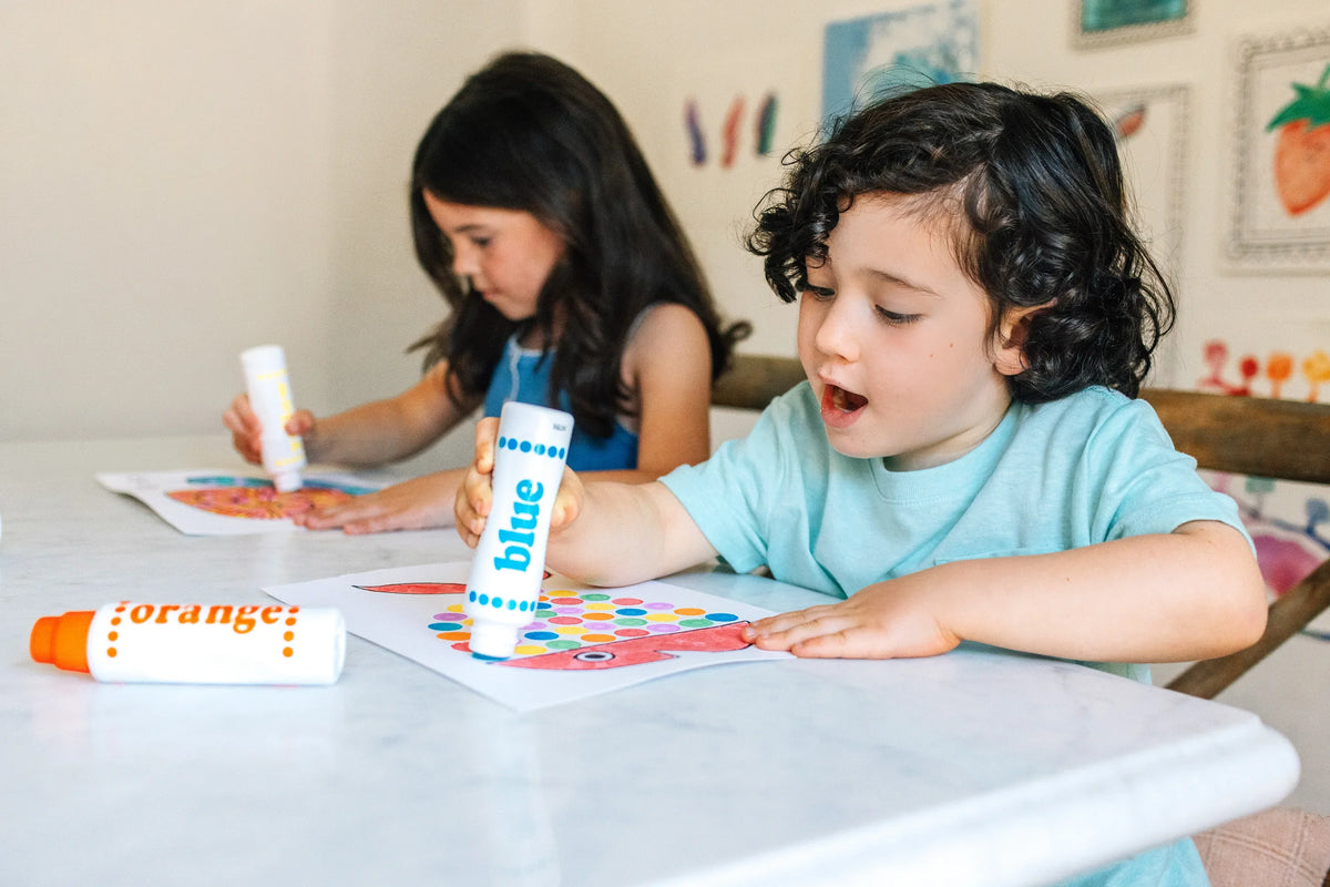 Two kids making dot art at the table with Rainbow Dot Markers