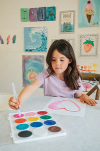 Girl painting a heart with a Swishies brush and Whirl of Color paints